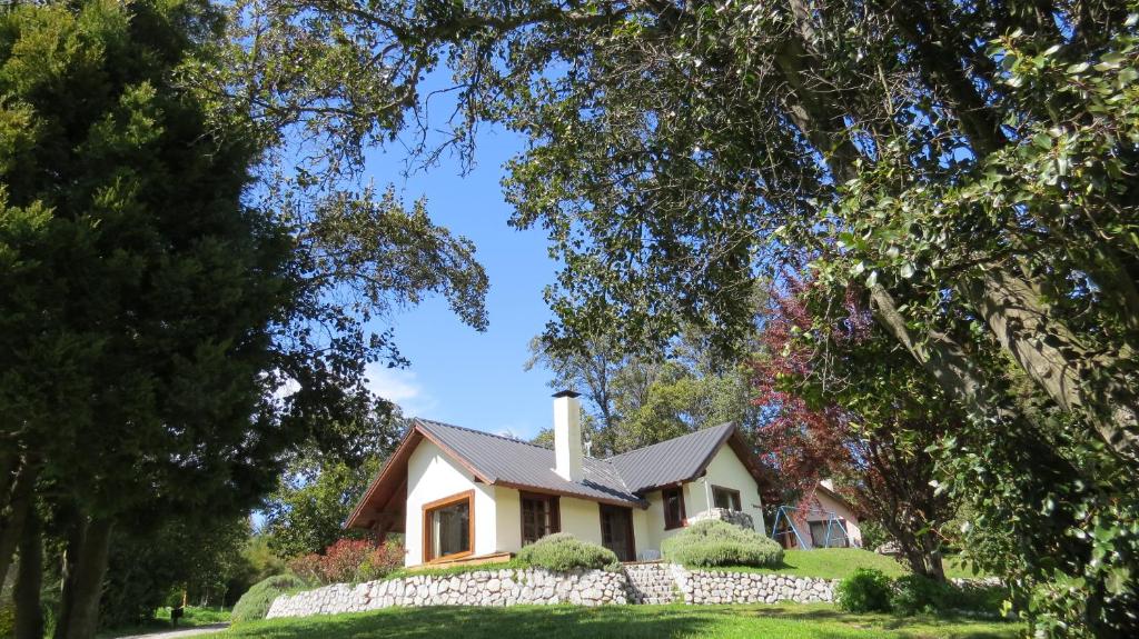 une maison avec une clôture en pierre devant elle dans l'établissement Cabañas & Aparts Lancuyen, Villa de Montaña, à Villa La Angostura