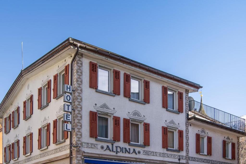 a building with red shuttered windows on top of it at Hotel Alpina in Zernez