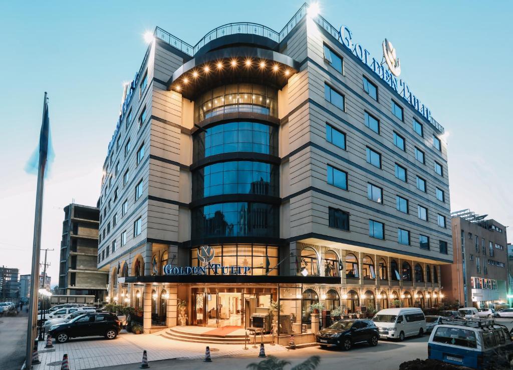 un gran edificio con coches estacionados frente a él en Golden Tulip Addis Ababa, en Addis Ababa