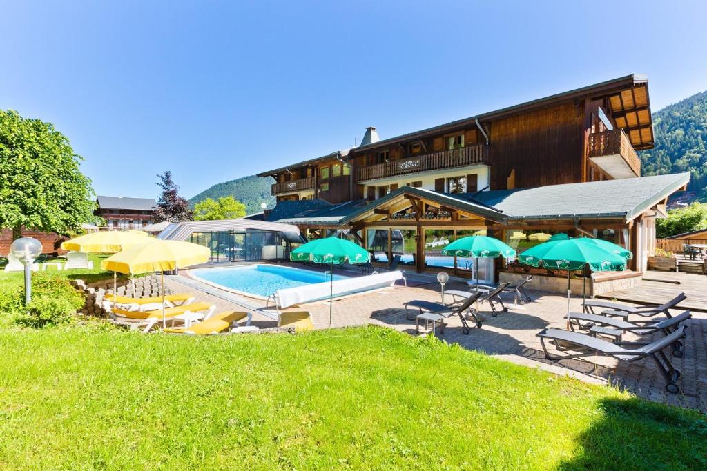 ein Hotel mit einem Pool, Stühlen und Sonnenschirmen in der Unterkunft Hotel Les Bruyères in Morzine