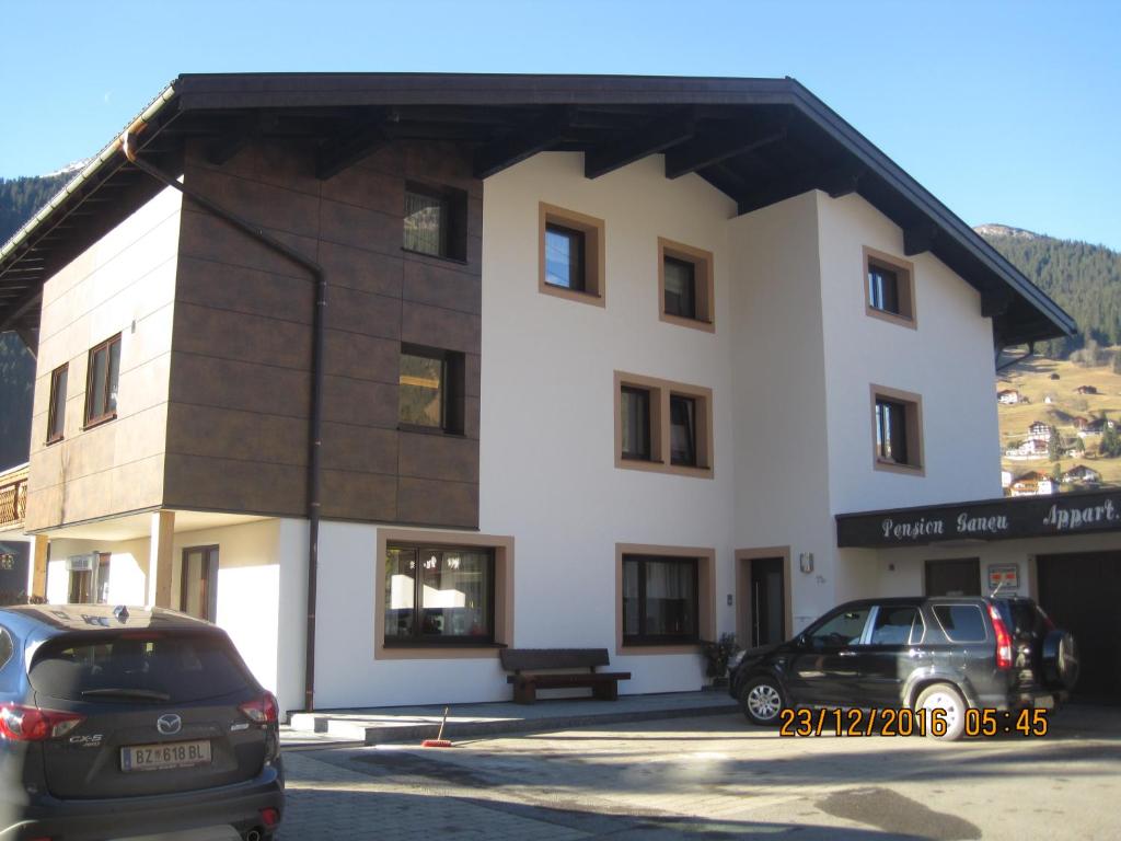 un grande edificio bianco con auto parcheggiate in un parcheggio di Haus Ganeu a Gaschurn