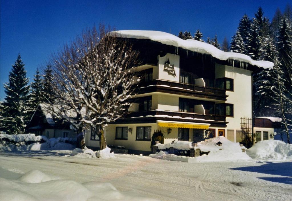 ein schneebedecktes Gebäude mit einem Baum davor in der Unterkunft Alpenhof Annaberg in Annaberg im Lammertal