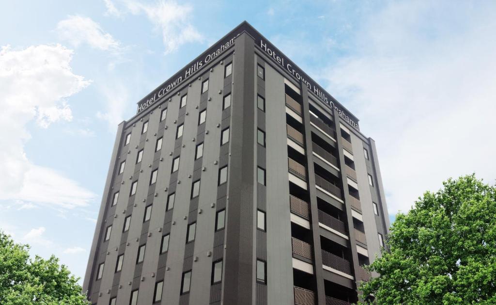 a tall gray building with trees in the foreground at Hotel Crown Hills Onahama in Iwaki