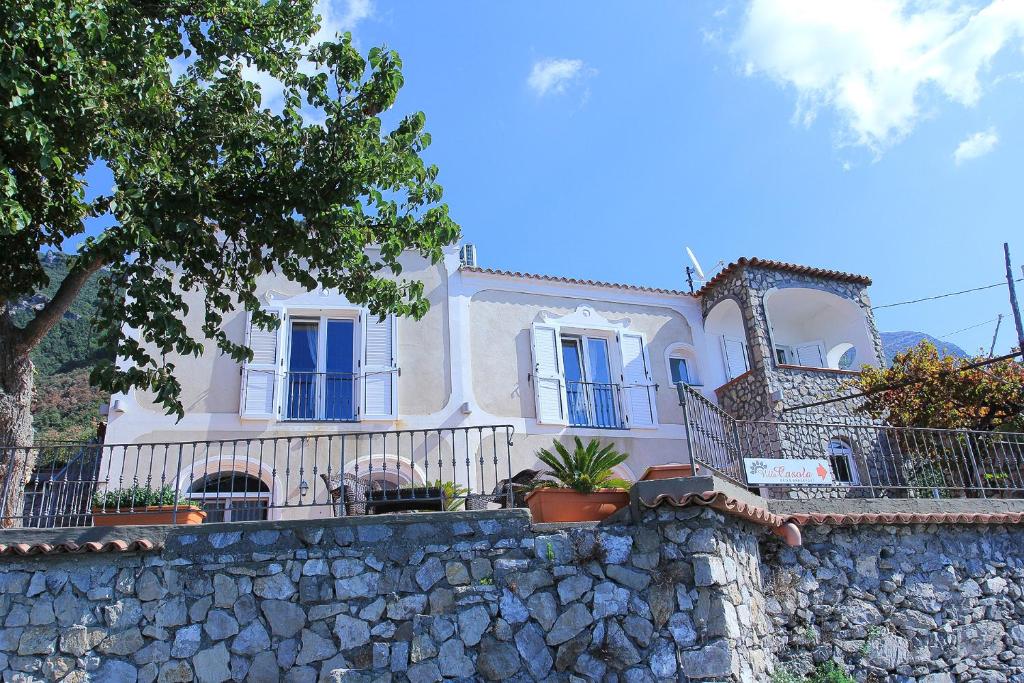 una casa bianca con finestre blu e un muro in pietra di Villa Casola B&B a Positano