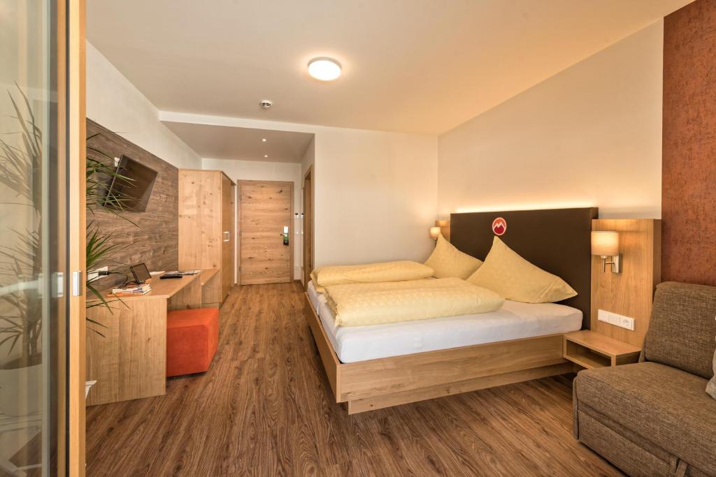 1 dormitorio pequeño con 1 cama y 1 sofá en Hotel Alpenfeuer Montafon, en Sankt Gallenkirch