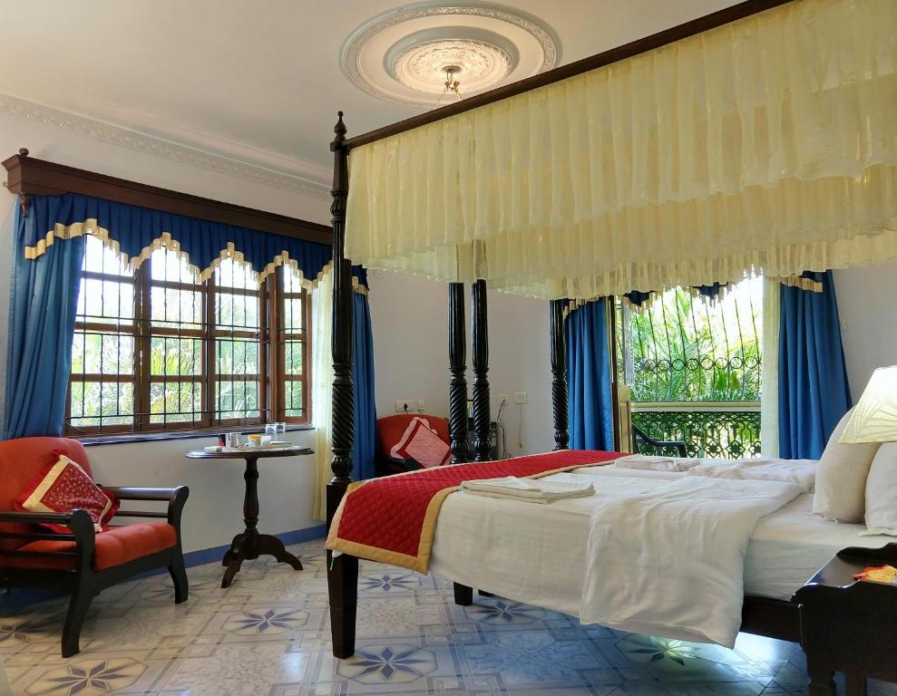 um quarto com uma cama, uma cadeira e janelas em Palm Grove Cottages - Leisure Resort em Benaulim