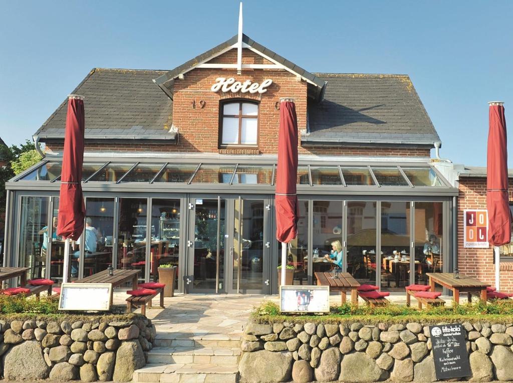 een restaurant met rode parasols voor een gebouw bij Hotel Kiose in Wenningstedt