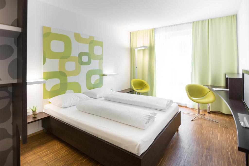 um quarto com uma cama e 2 cadeiras amarelas em arte Hotel Krems em Krems an der Donau