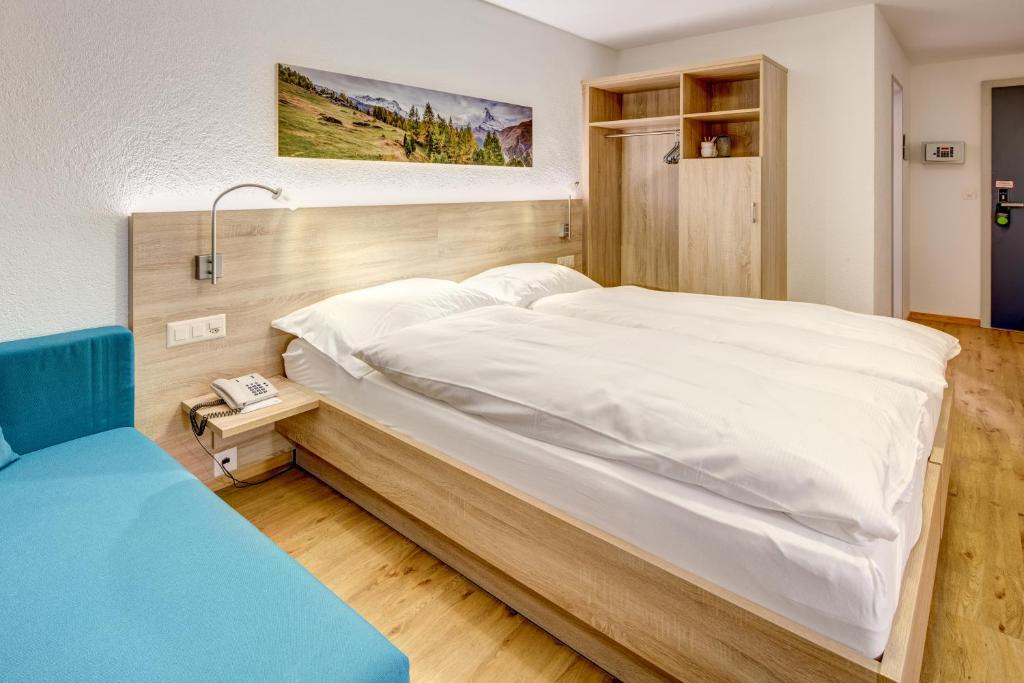 una camera con un grande letto bianco di Hotel Matterhorn Inn a Täsch