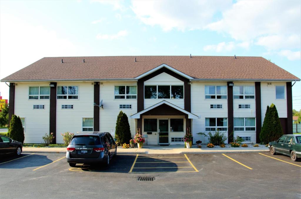 un grande edificio bianco con auto parcheggiate in un parcheggio di Royal Windsor Motel a Windsor