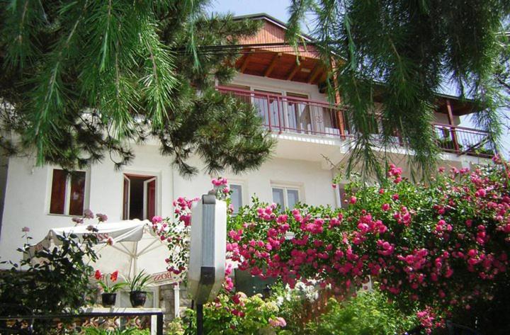 een wit huis met roze bloemen ervoor bij Bache Apartments in Ohrid