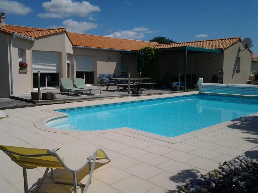 - une piscine avec une table et des chaises à côté d'une maison dans l'établissement La Chambre des Amis, à Parthenay