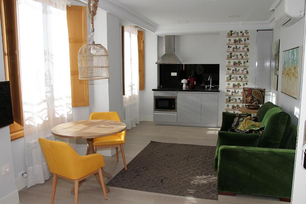 a living room with a table and a green couch at Principia Suites in León