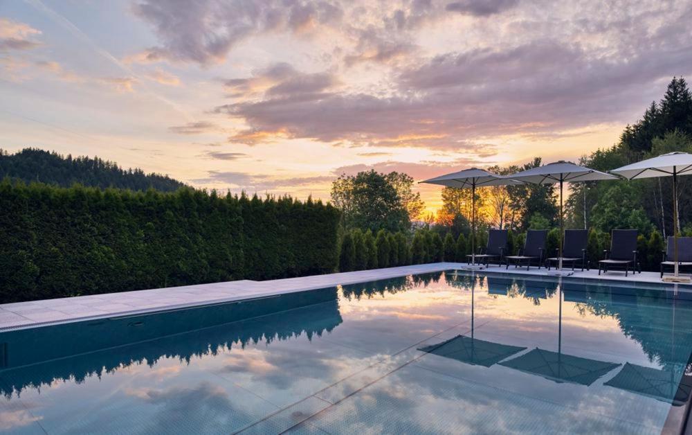 una piscina con sedie e ombrelloni di Wellness- und Vitalhotel Böhmhof a Bodenmais