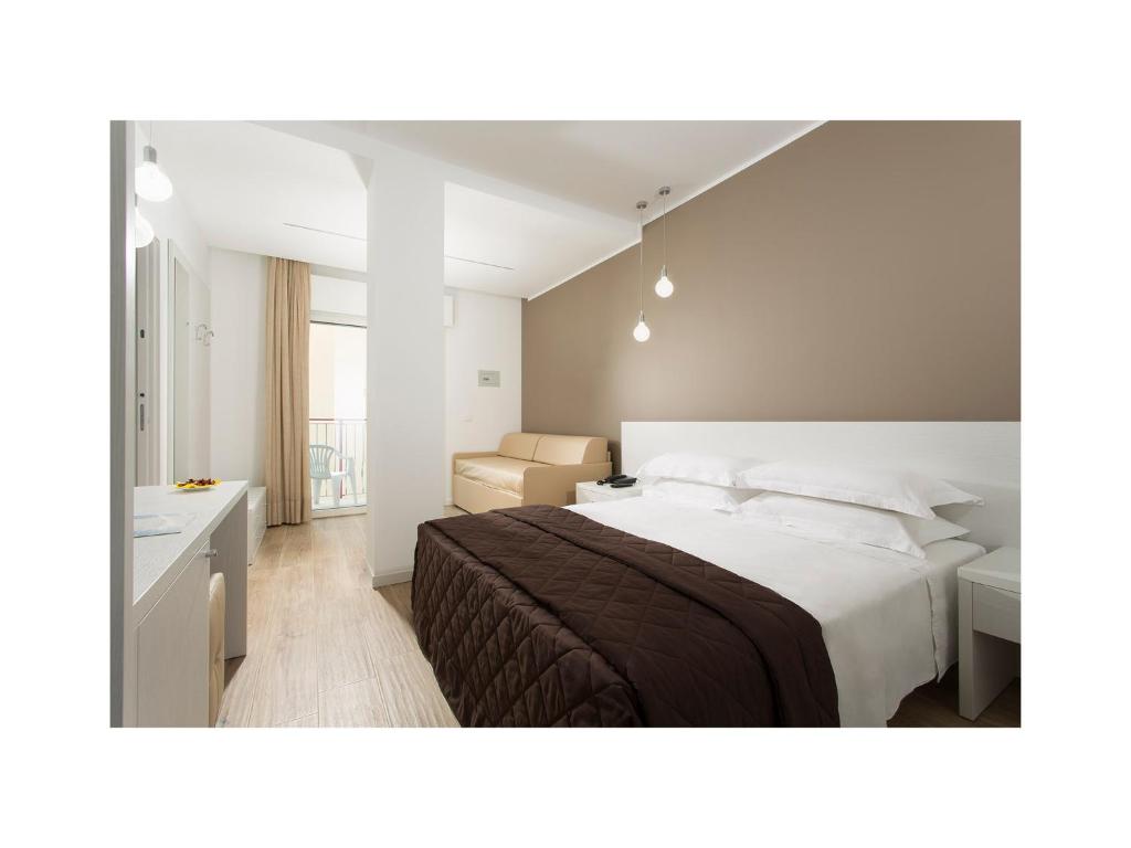 a bedroom with a large white bed and a desk at Hotel Gardenia in Lido di Jesolo