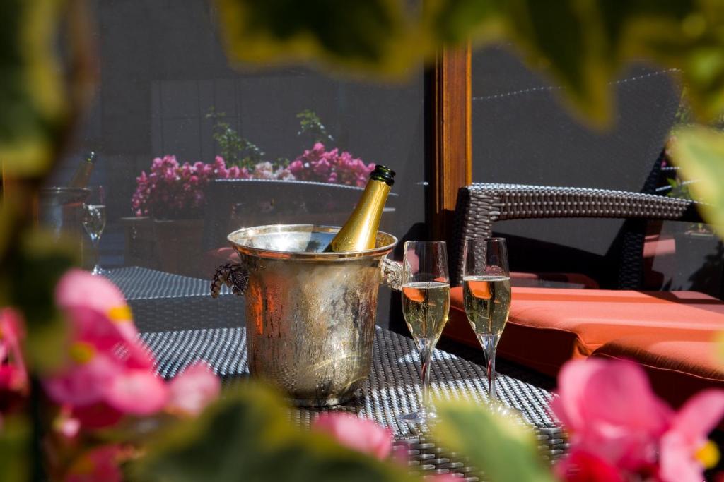 Una botella de champán en un cubo sobre una mesa con dos copas. en Nicey - Hôtel Spa, Lounge, Coworking, en Romilly-sur-Seine