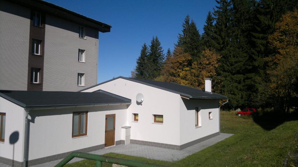 a white house with a black roof next to a building at Apartmán Srní in Srní