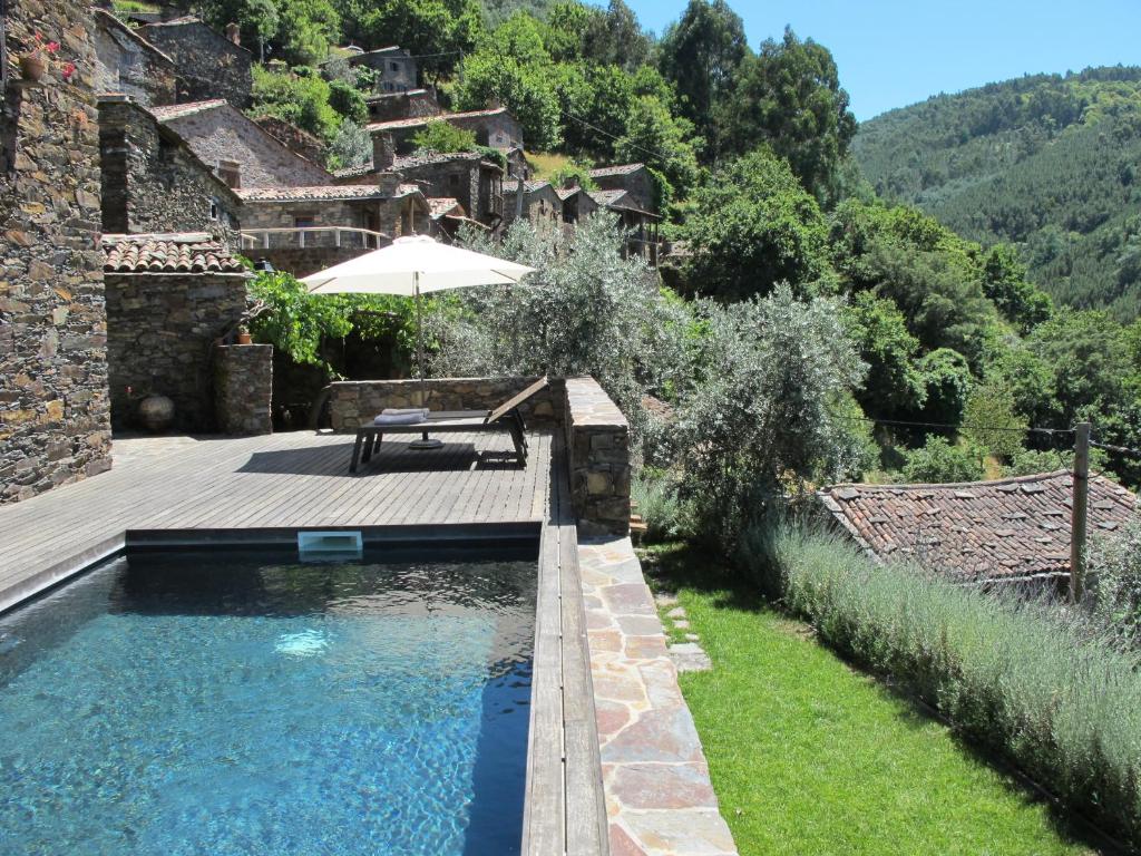 a pool with a wooden deck and an umbrella at Casa do Talasnal in Lousã