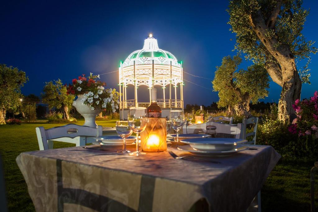 - une table avec des verres à vin et un kiosque la nuit dans l'établissement Agriturismo Li Calizzi Arte e Natura, à Novoli