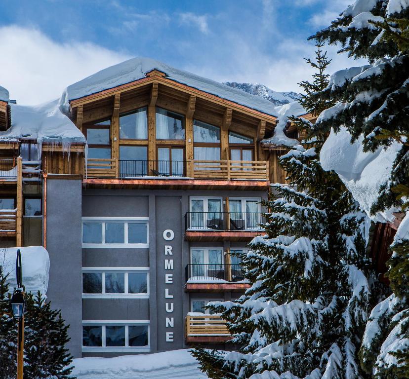 een groot gebouw met sneeuw bedekte bomen ervoor bij Hotel Ormelune in Val dʼIsère