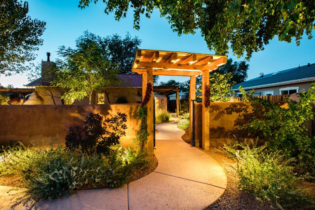 een houten pergola in een tuin met een stoep bij Casa La Huerta in Albuquerque