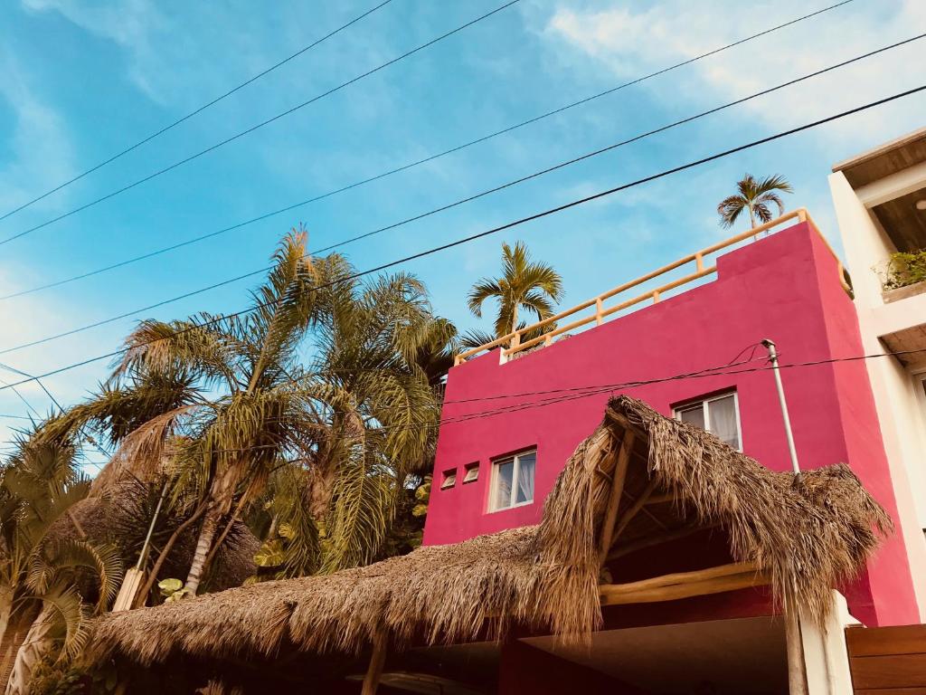 a pink building with palm trees in front of it at Cozy Little Apartment in Sayulita