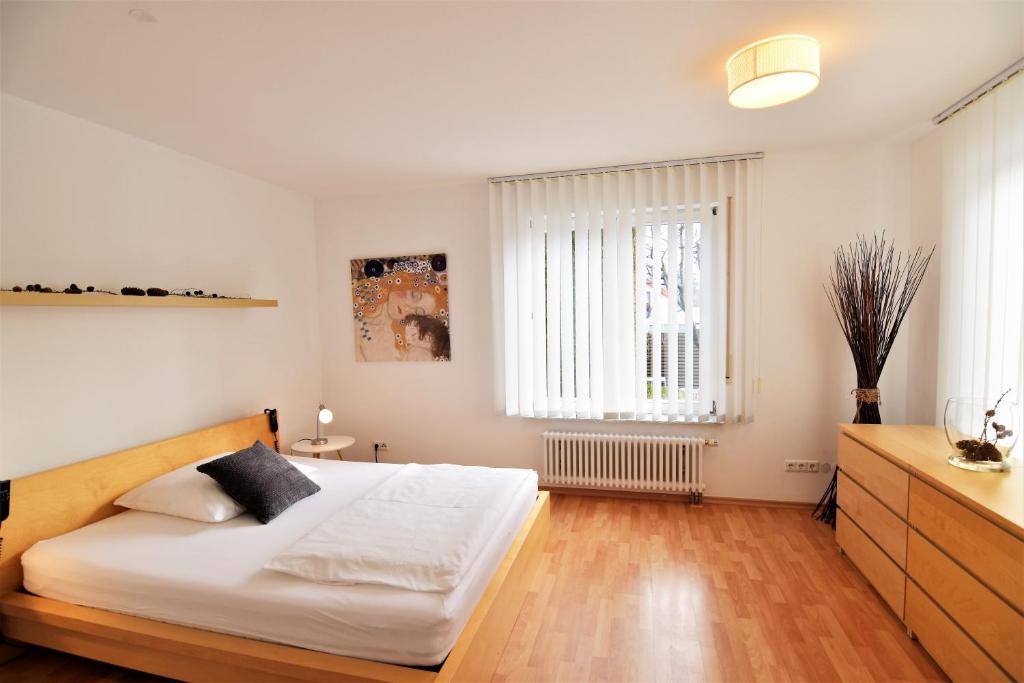 a white bedroom with a bed and a window at Apartment D&D Spessart in Ettlingen