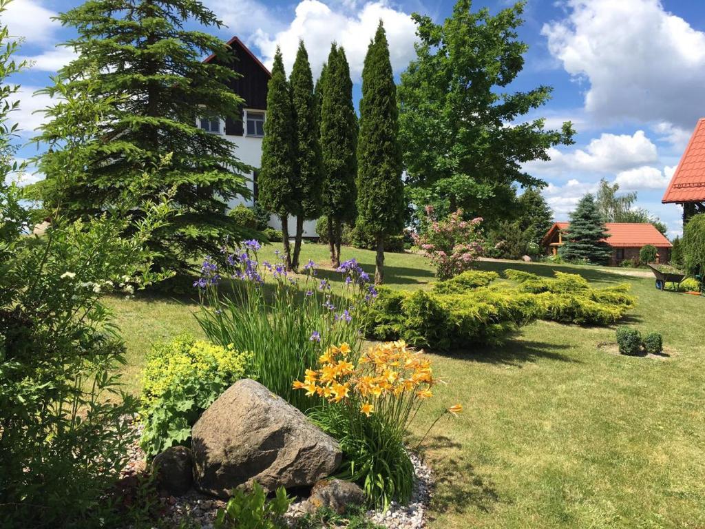 un giardino con fiori e alberi e una casa di Haus Masur a Mikołajki