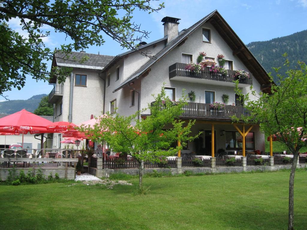 - un grand bâtiment blanc avec un balcon et des tables dans l'établissement Dormio Gasthof Höllwirt, à Obertraun