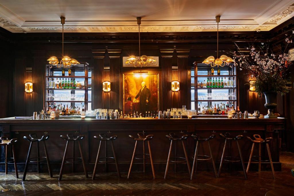 a bar in a room with windows and a painting at Freehand New York in New York