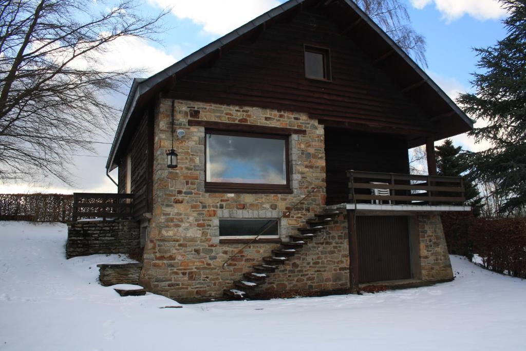 um pequeno edifício de tijolos com janela e escadas na neve em Le Piroy em Saint-Hubert