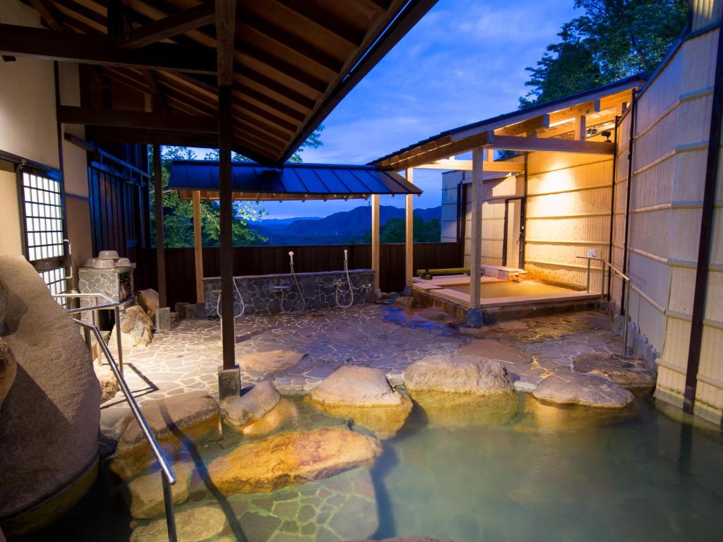 uma piscina de água com pedras em frente a um edifício em Arima Onsen Motoyu Ryuusenkaku em Kobe