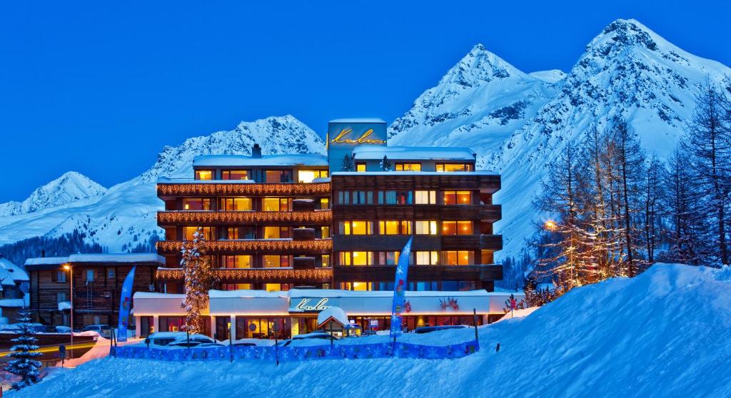 um hotel na neve à noite com montanhas cobertas de neve em Arosa Kulm Hotel & Alpin Spa em Arosa