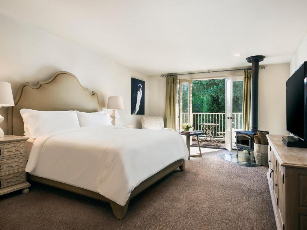 - une chambre avec un grand lit blanc et un balcon dans l'établissement Mill Valley Inn, à Mill Valley