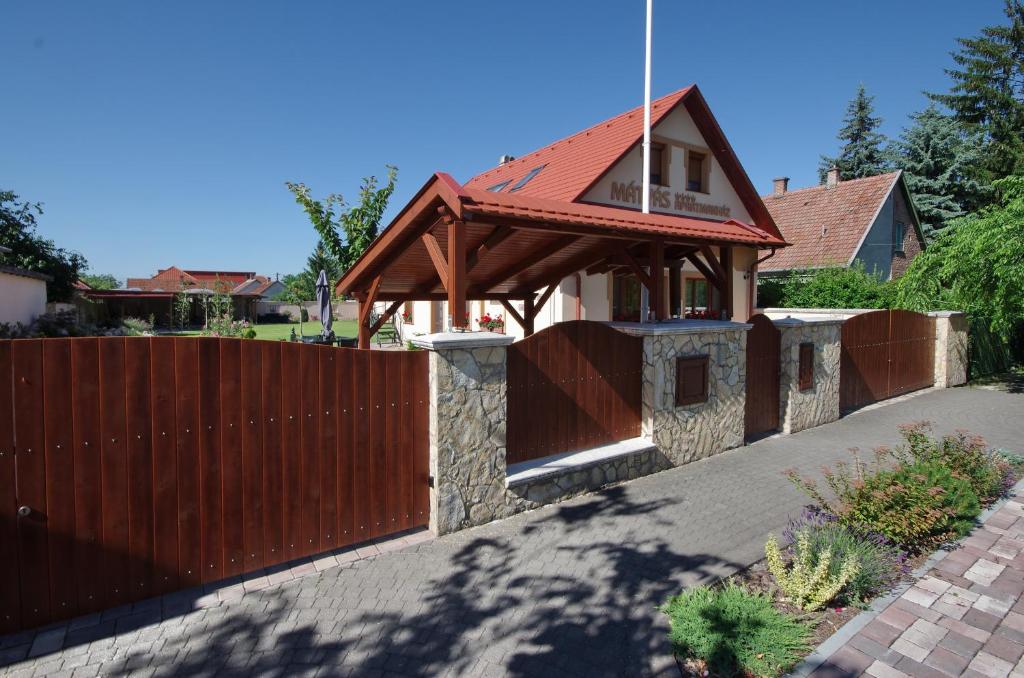 a house with a fence and a wooden gate at Mátyás Apartmanház in Gyula