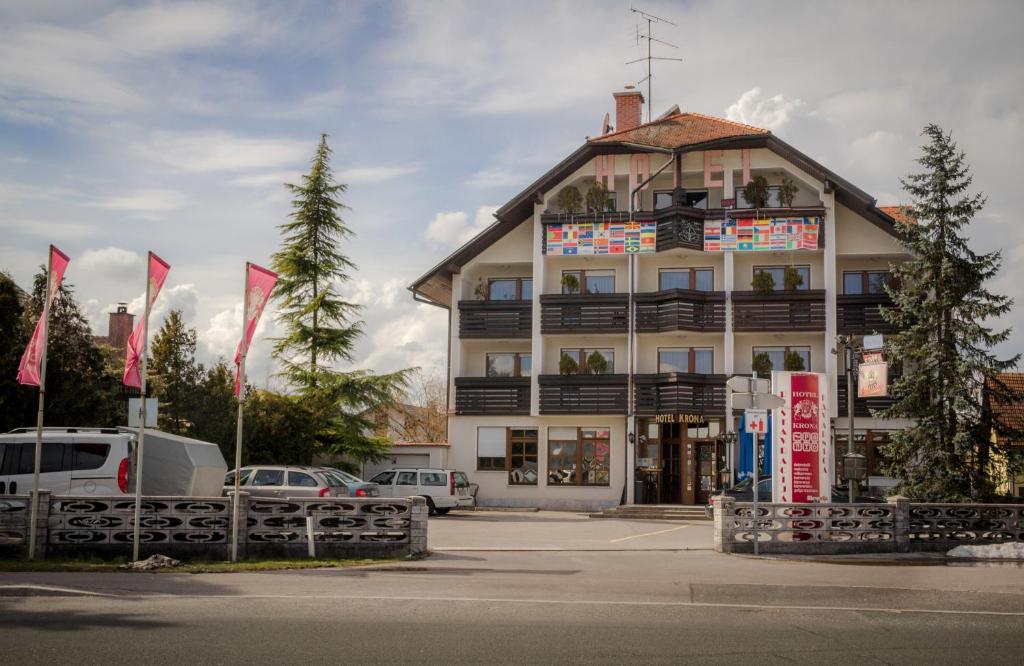 een groot gebouw met vlaggen ervoor bij Hotel Krona Domžale in Domžale