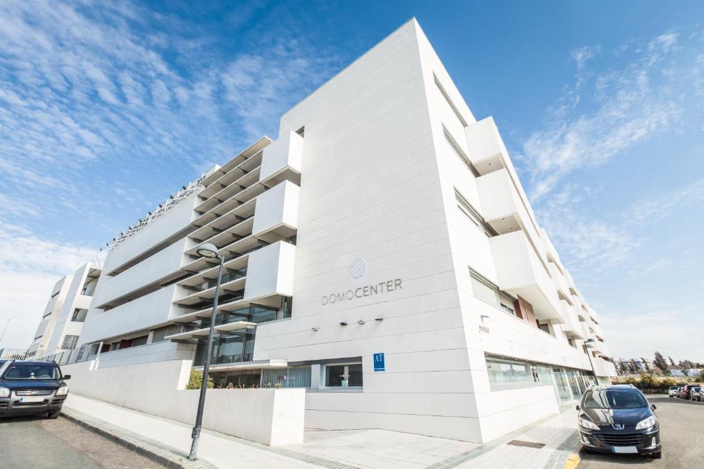 a white building with cars parked in front of it at Domocenter Apartamentos Turísticos in Bormujos