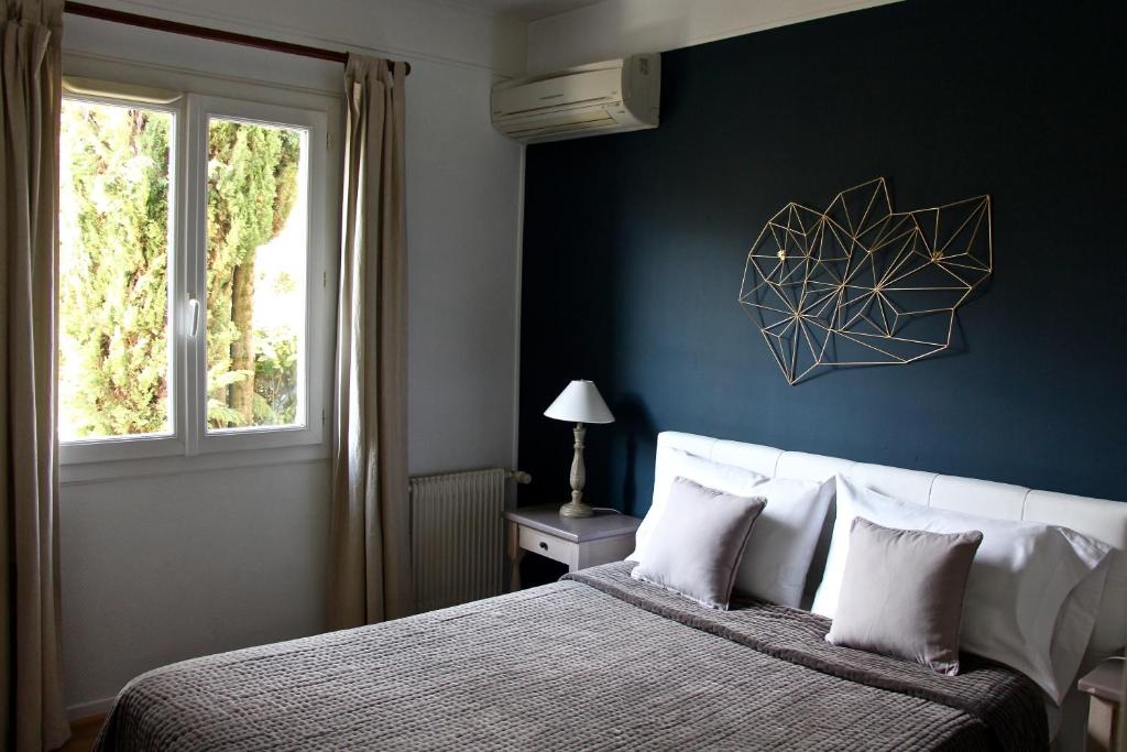 Schlafzimmer mit einem Bett mit blauer Wand in der Unterkunft Hotel Les Oliviers in Draguignan