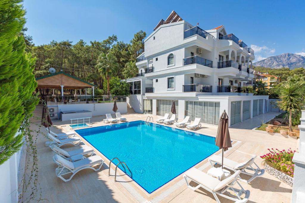 une grande maison blanche avec une piscine et des chaises dans l'établissement Forest Park Hotel, à Kemer