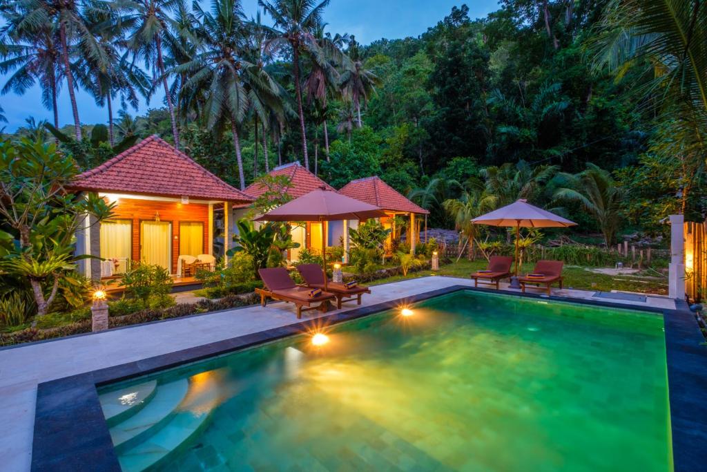 uma piscina com cadeiras e guarda-sóis em frente a uma casa em Crystal Bay Bungalows em Nusa Penida