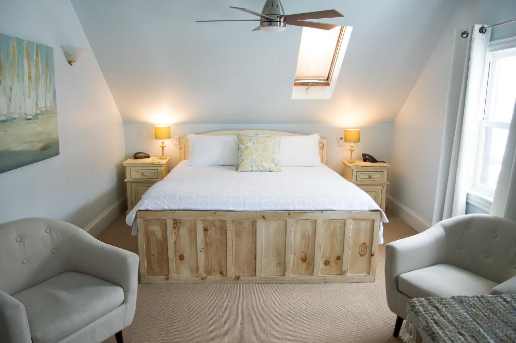 a bedroom with a bed and two chairs at Salt Shaker Deli & Inn in Lunenburg