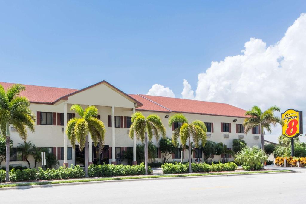 een hotel met palmbomen ervoor bij Super 8 by Wyndham Pompano Beach in Pompano Beach