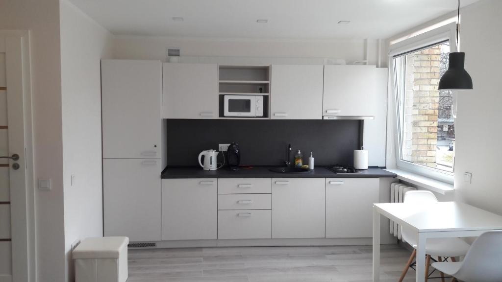 cocina blanca con armarios blancos y microondas en Anykščiai Center Apartment, en Anykščiai