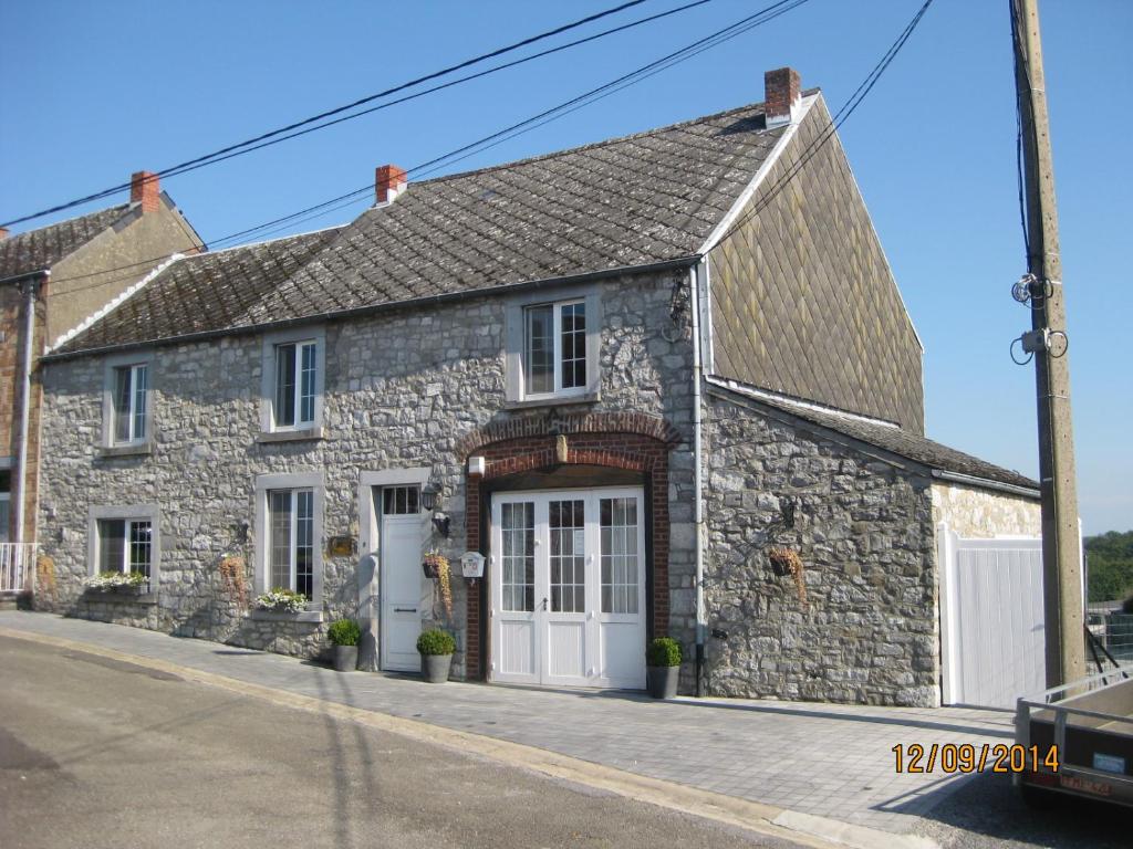 a stone house with a white door on a street at Gîte du Soleil in Anhée