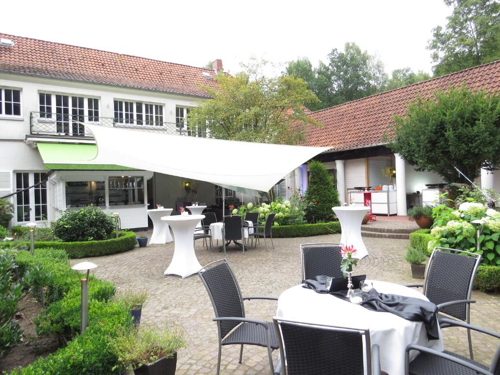 un patio con tavoli e sedie bianchi e un edificio di Gästehaus Villa Wolff a Bomlitz