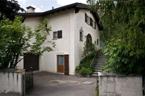 a large white house with a staircase in front of it at Studio in Chasa Quirin in Zernez