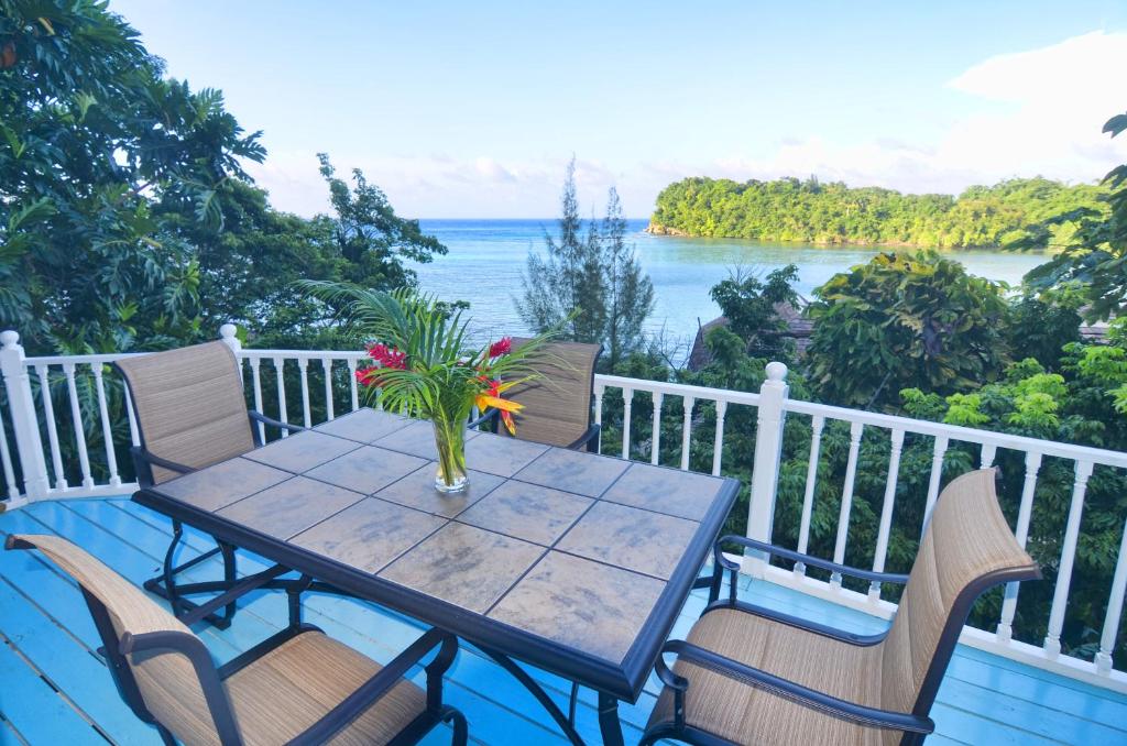 een tafel en stoelen op een balkon met uitzicht op de oceaan bij Moon San Villa at the Blue Lagoon in Port Antonio