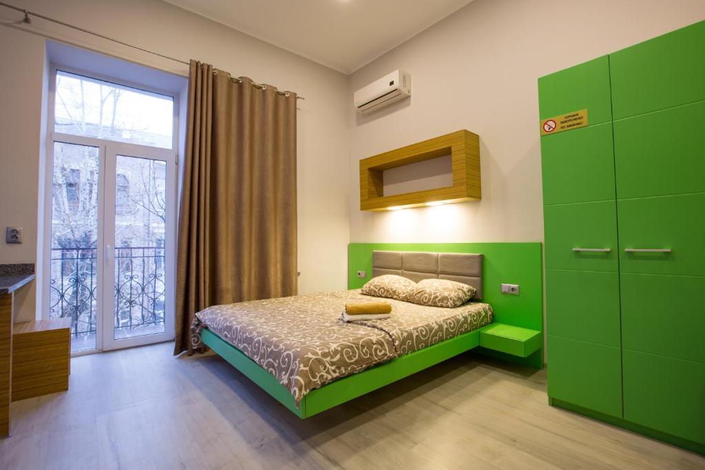 um quarto verde com uma cama e uma janela em Pushkinskaya Apartments em Carcóvia