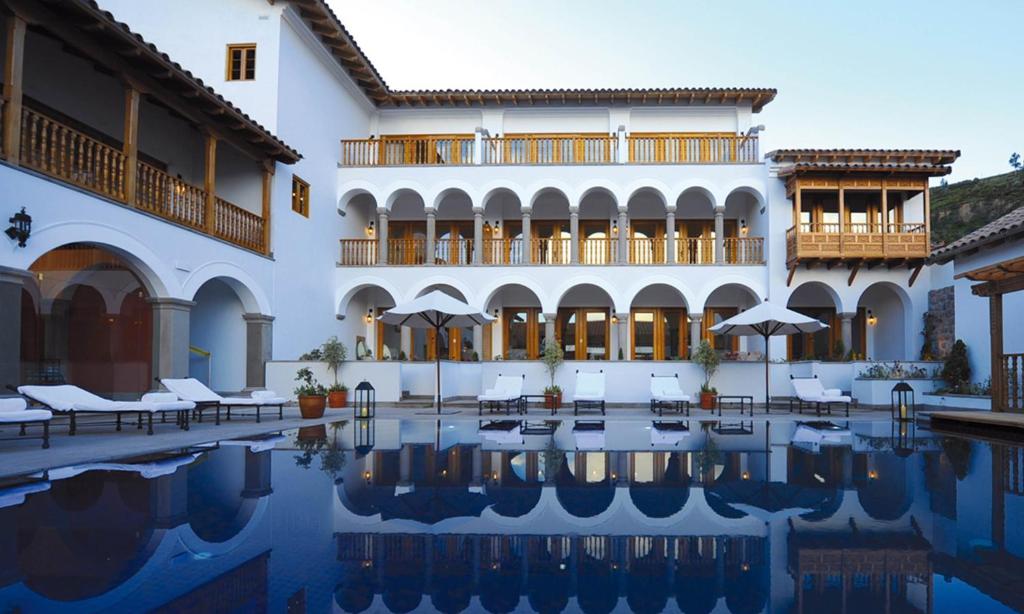 un hôtel avec une piscine en face d'un bâtiment dans l'établissement Palacio Nazarenas, A Belmond Hotel, Cusco, à Cusco