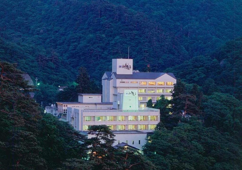 een groot gebouw aan de zijkant van een berg bij Higashiyama Park Hotel Shinfugetsu in Aizuwakamatsu